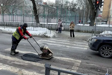 Дорожній працівник ремонтує аварійну яму на проїжджій частині дороги методом «холодного асфальтування». Фото із відкритих джерел