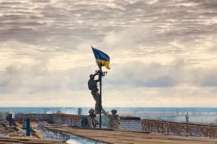 Українські військові встановлюють державний прапор на даху лікарні у визволеному Високопіллі.