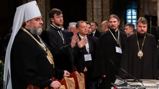 На цій світлині двоє ієрархів УПЦ (МП) під час Об'єднавчого собору: митрополит Вінницький і Барський Симеон (ліворуч) і митрополит Переяслав-Хмельницький і Вишневський Олександр (в миру Олександр Драбинко, праворуч). Київ, 15 грудня 2018 року