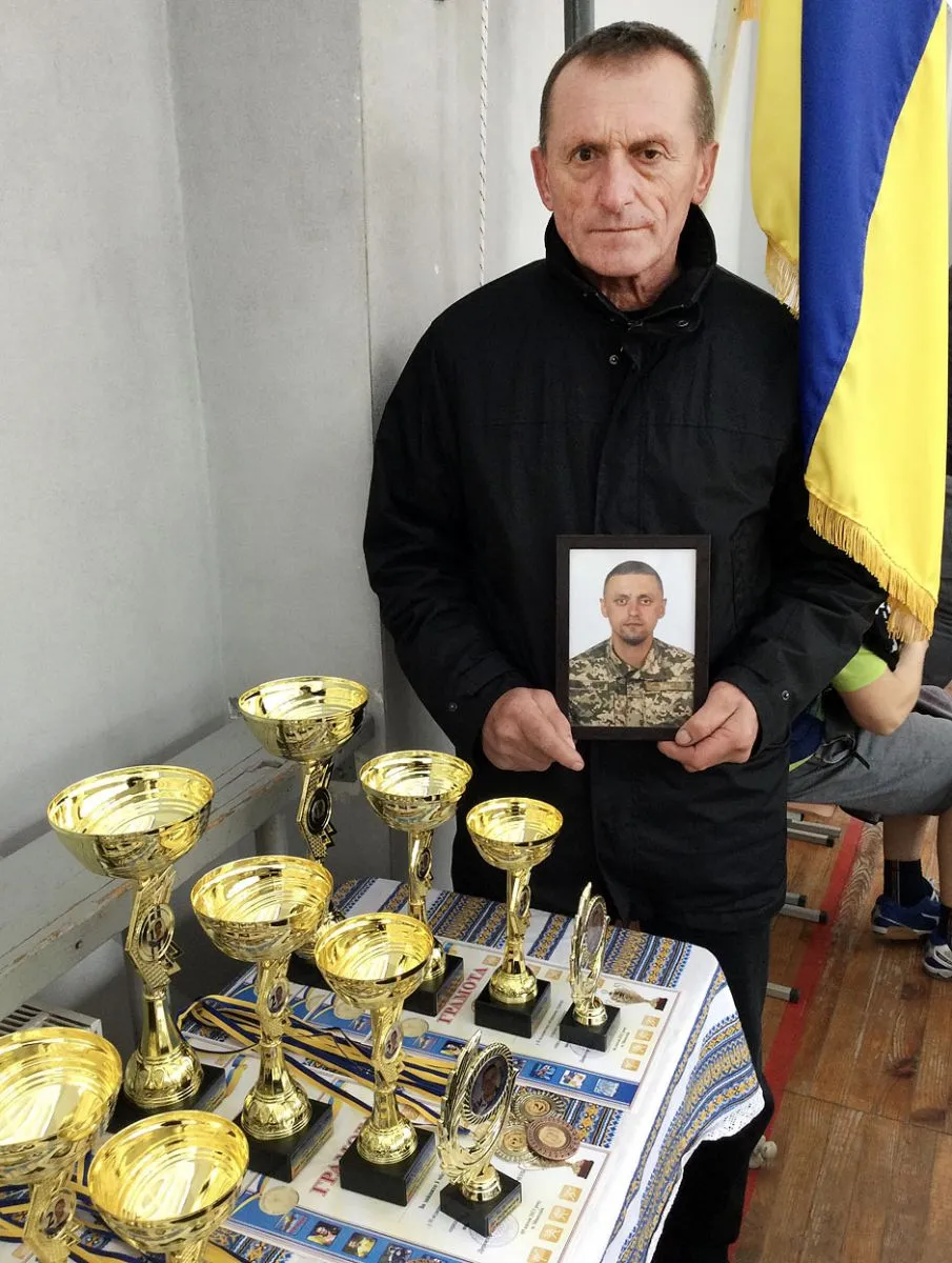 Ігор Оприск із портретом сина біля спортивних нагород на змаганнях у пам’ять про нього. Фото автора.