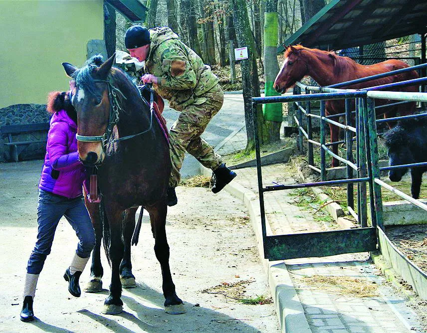 Інструкторка допомагає воїну. В іпотерапії важливо бути поруч із тим, хто навчається