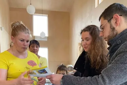 Отець Іван Данилів вручає ваучер на суму 1500 гривень молодій породіллі.