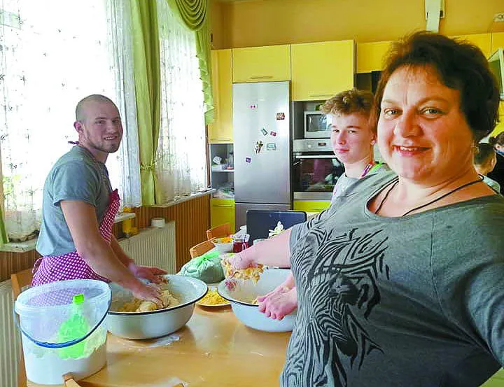 ...а старших хлопців вчить замішувати тісто.